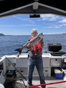 A old man holding a big fish on a boat with water all around