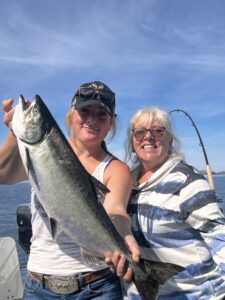 two woman holding a big fish on a boat and smiling