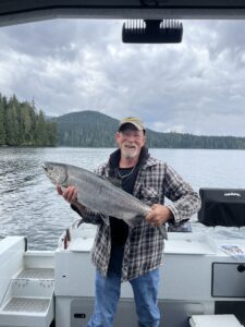 A man holding a fish on a boat and smiling