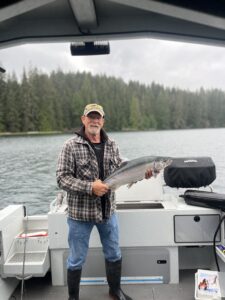 A man holding a fish on a boat and smiling.