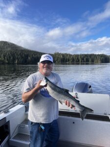 A man holding a fish on a boat and smiling.