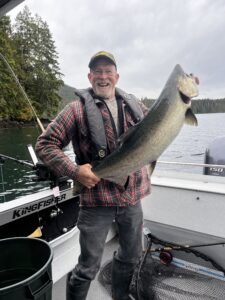 A man holding a fish on a boat and smiling.