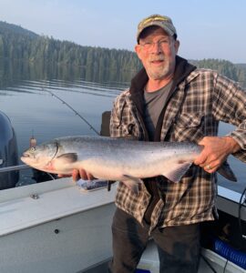 A man holding a fish on a boat and smiling.