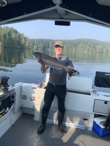 A man holding a fish on a boat and smiling.