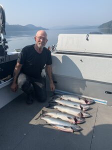 A man holding a fish on a boat and smiling.